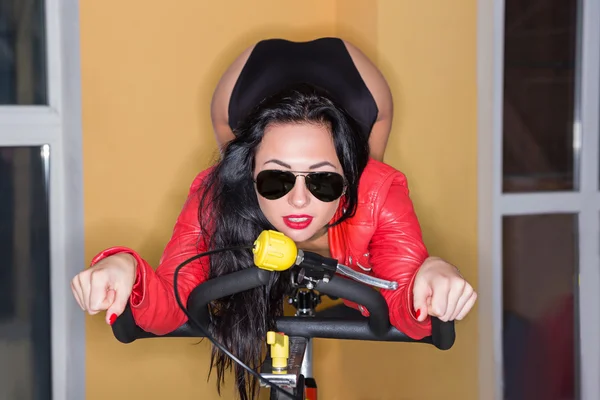 Mujer joven entrenando en bicicleta de ejercicio —  Fotos de Stock