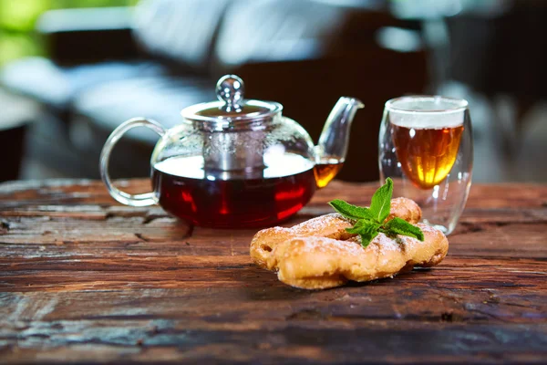 おいしいエクレアと木製のテーブルに紅茶のカップ — ストック写真