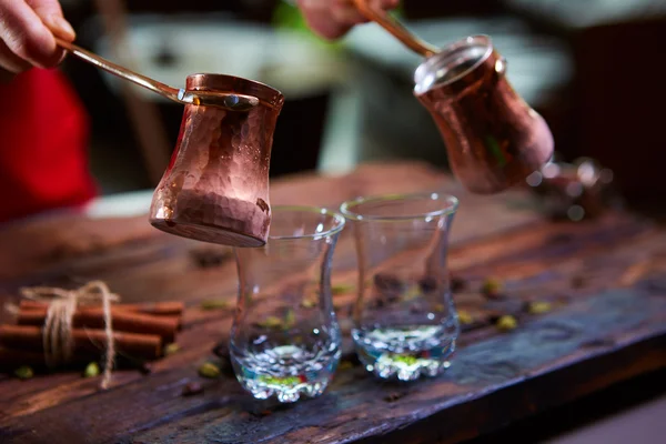 Despejar o café árabe em xícaras no fundo de madeira . — Fotografia de Stock