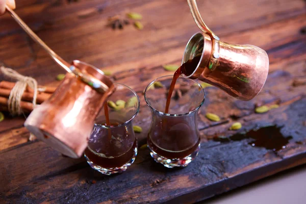 Despejar o café árabe em xícaras no fundo de madeira . — Fotografia de Stock