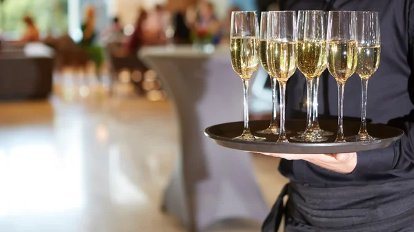 Pincér szolgáló pezsgő, egy tálcán — Stock Fotó