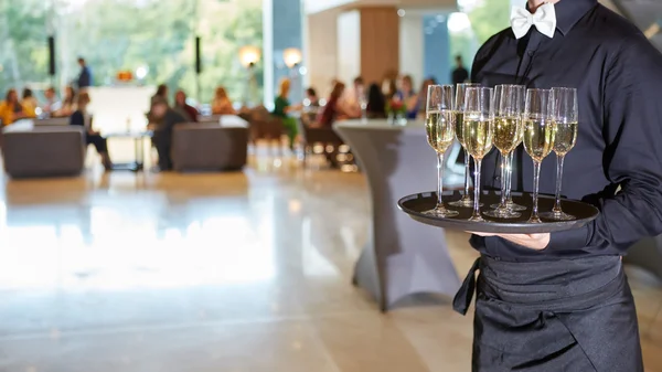 Waiter serving champagne on a tray — Stock Photo, Image