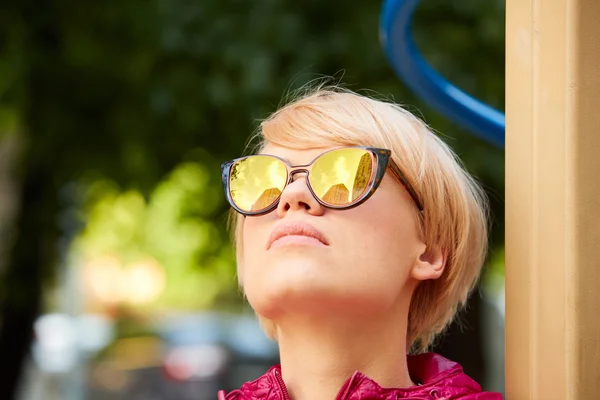 Mujer joven con cabello rubio usando gafas de sol — Foto de Stock