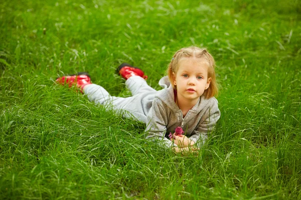 Portret van meisje liggend op groen gras — Stockfoto