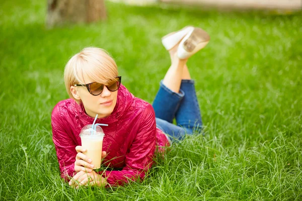 Hermosa joven mujer disfruta de beber café y acostado en la hierba — Foto de Stock