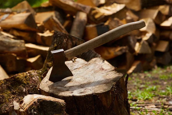 Old ax on log and firewood in the background — Stock Photo, Image