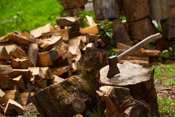 Old ax on log and firewood in the background — Stock Photo, Image