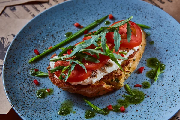 Bruschetta with cottage cheese, tomatoes and arugula served on blue plate. — Stock Photo, Image
