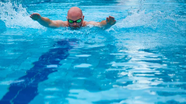 Young man in goggles swim using butterfly technique — Stock Photo, Image