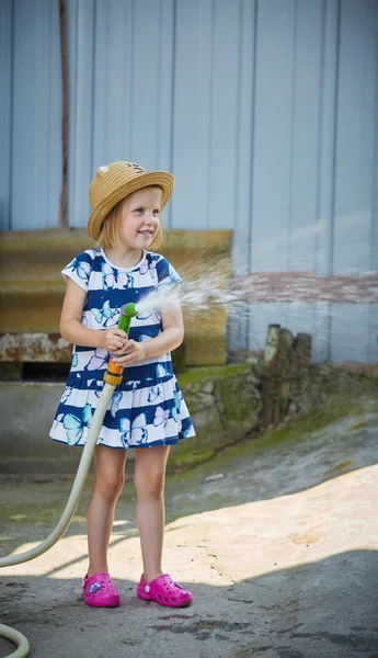 Piccola ragazza felice irrigazione giardino — Foto Stock