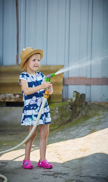 Kleines glückliches Mädchen wässert Garten — Stockfoto