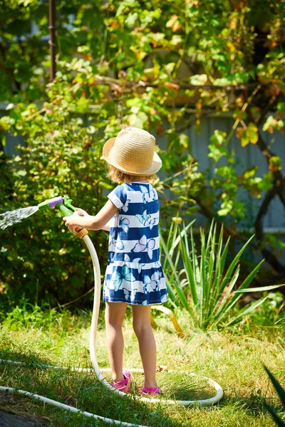 Kleines glückliches Mädchen wässert Garten — Stockfoto