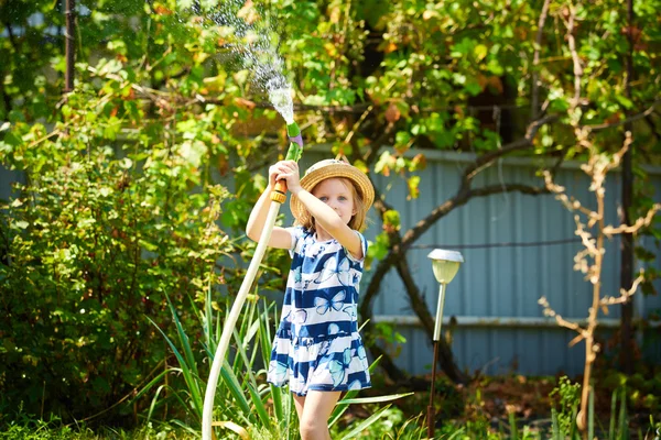 Piccola ragazza felice irrigazione giardino — Foto Stock