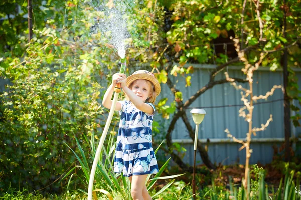 Piccola ragazza felice irrigazione giardino — Foto Stock