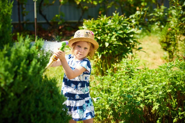 Kleines glückliches Mädchen wässert Garten — Stockfoto