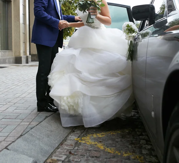 Hermosa pareja, novia y novio entrar en la limusina de la boda — Foto de Stock