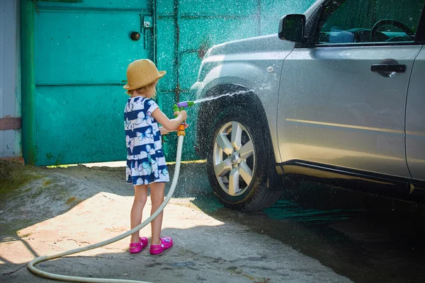Little girl helps her parents to wash the car