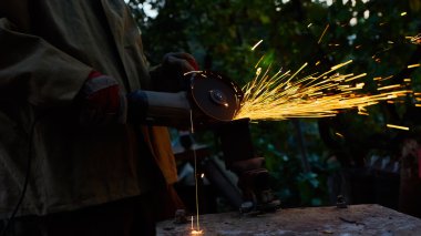 Öğütücüyle metal kesen bir işçi. Demir öğütürken kıvılcımlar