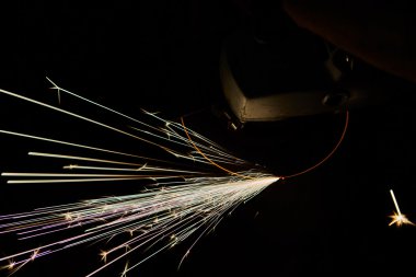 Öğütücüyle metal kesen bir işçi. Demir öğütürken kıvılcımlar