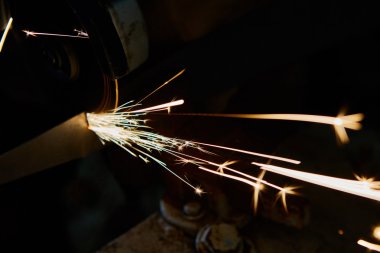 Öğütücüyle metal kesen bir işçi. Demir öğütürken kıvılcımlar