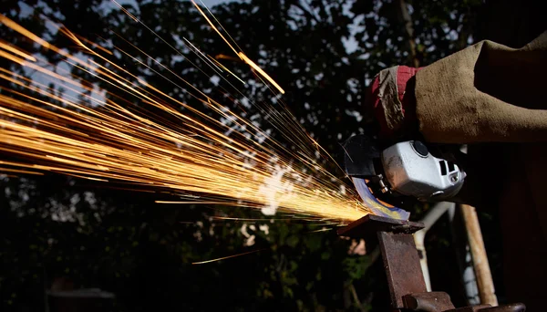 Trabajador de corte de metal con amoladora. Chispas mientras moliendo hierro —  Fotos de Stock