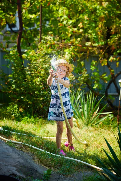 Piccola ragazza felice irrigazione giardino — Foto Stock