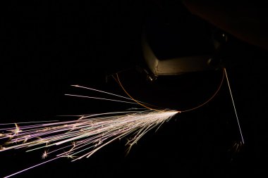 Öğütücüyle metal kesen bir işçi. Demir öğütürken kıvılcımlar