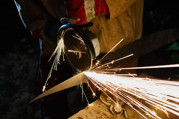 Robotnik obcinający metal szlifierką. Iskry podczas mielenia żelaza — Zdjęcie stockowe