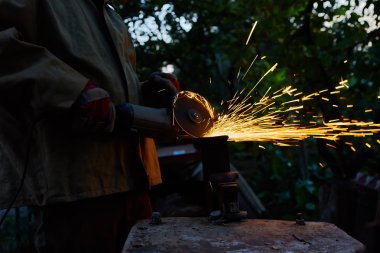 Öğütücüyle metal kesen bir işçi. Demir öğütürken kıvılcımlar