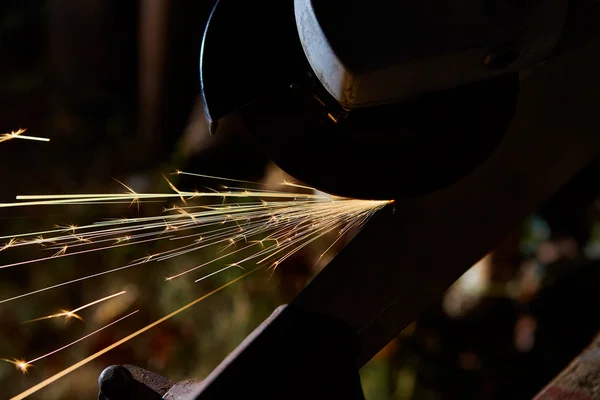 Robotnik obcinający metal szlifierką. Iskry podczas mielenia żelaza — Zdjęcie stockowe