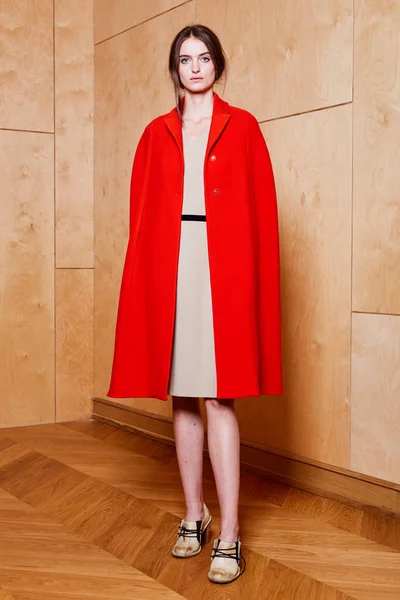 Ung smal modell klädd i röd rock i studio — Stockfoto