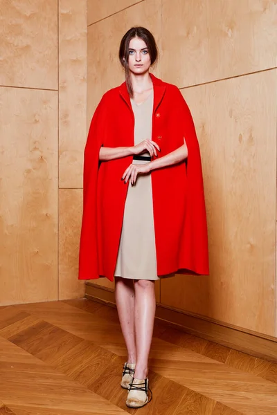 Young slim model wearing red coat in studio — Stock Photo, Image