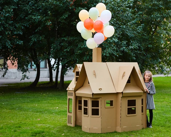 Criança brincando em um playhouse de papelão. Conceito ecológico — Fotografia de Stock