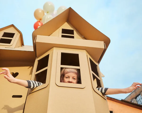 Criança brincando em um playhouse de papelão. Conceito ecológico — Fotografia de Stock