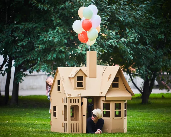 Happy educator playing with girl in playhouse in kindergarten — Stock Photo, Image