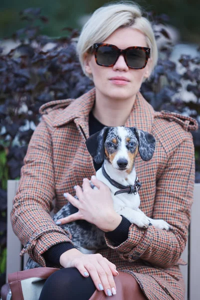 Huisdierenzorg concept. Jonge vrouw die haar teckel hond buiten in haar armen houdt. Focus op hond — Stockfoto