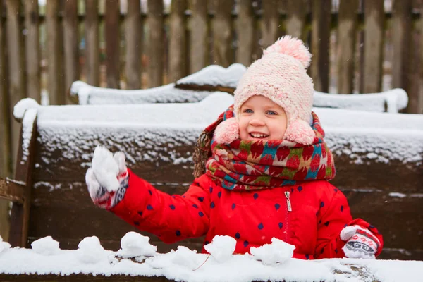 Speels meisje heeft een leuke wintertijd in een snowpark. Schattig speels meisje outdoor genieten van eerste sneeuw. — Stockfoto