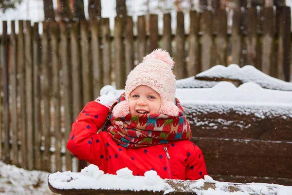 Winter meisje gooien sneeuwbal op camera glimlachend gelukkig plezier hebben buiten op sneeuwen winterdag spelen in de sneeuw. Schattig speels meisje outdoor genieten van eerste sneeuw — Stockfoto