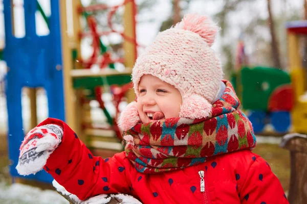 Chica de invierno lanzando bola de nieve a la cámara sonriendo feliz divirtiéndose al aire libre en el día de invierno nevando jugando en la nieve. Linda chica juguetona al aire libre disfrutando de la primera nieve —  Fotos de Stock
