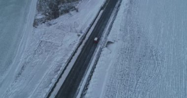Sonsuz asfalt yolu kış gezisi. Tek başına otoyolda tek başına giden bir araba. Hava aracı görüntüleri.