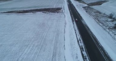 Sonsuz asfalt yolu kış gezisi. Tek başına otoyolda tek başına giden bir araba. Hava aracı görüntüleri.