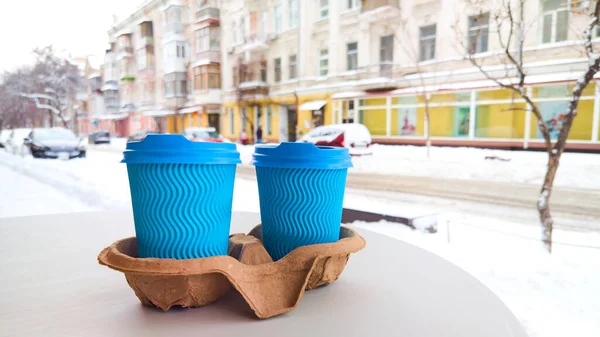 Две Blue Paper Cup с кофе на столе на улице. Размытый зимний фон — стоковое фото