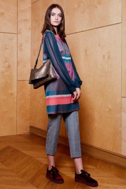 Havalı aksesuarlar takan güzel, şık bir kadının kapalı mekândaki portresi. Kadın modası, güzellik ve reklam konsepti. Metin için alanı kopyala.