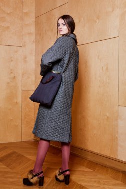 Havalı aksesuarlar takan güzel, şık bir kadının kapalı mekândaki portresi. Kadın modası, güzellik ve reklam konsepti. Metin için alanı kopyala.