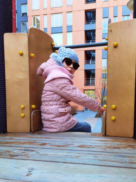9歳の少女は遊び場で。子供は暖かい半季節の服ピンクのジャケットとグレーの帽子を着ています. — ストック写真