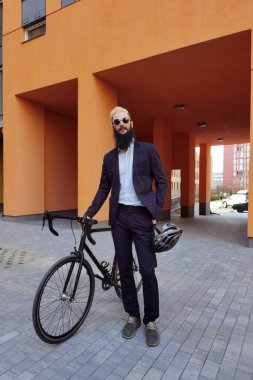 Bisikletinin yanında poz veren şık bir hippi..