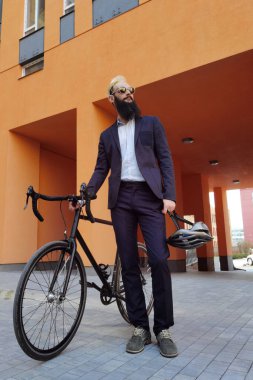 İşe giderken bisiklet süren genç ve şık bir işadamı..