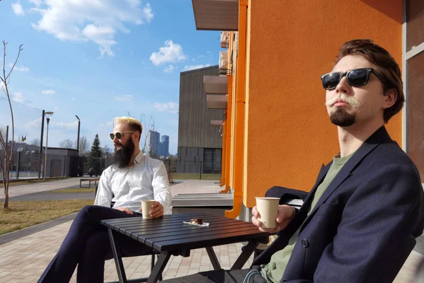 Dua pemuda hipster duduk di kafe mengobrol dan minum kopi — Stok Foto