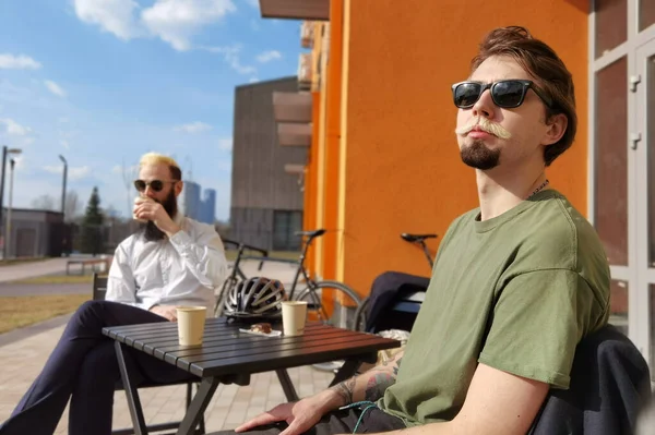 Dos jóvenes hipsters sentados en un café charlando y bebiendo café — Foto de Stock