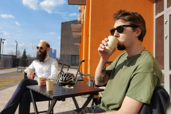 Due giovani hipster seduti in un caffè a chiacchierare e bere caffè — Foto Stock